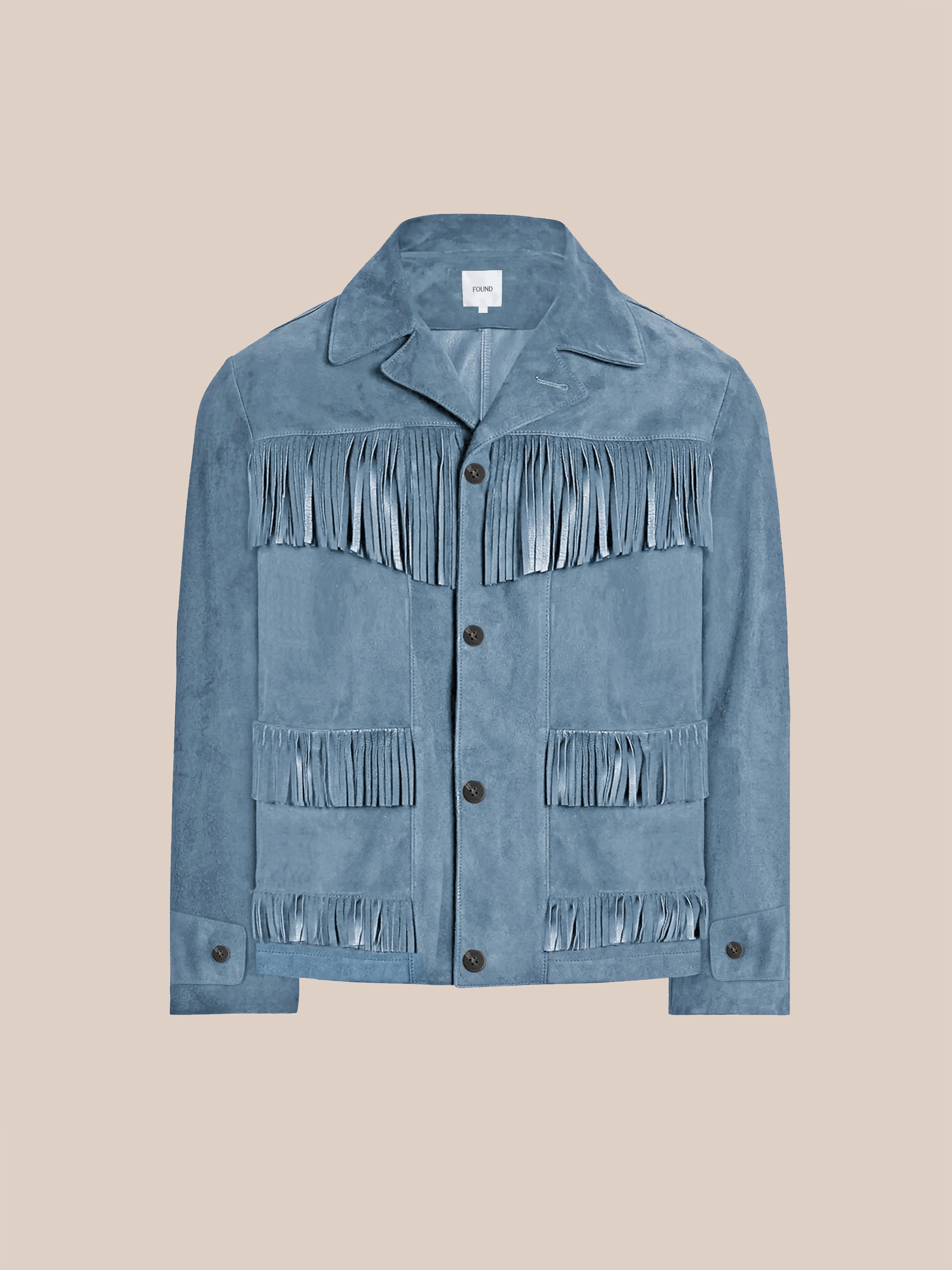 The FOUND Western Suede Fringe Jacket in light blue features a collar, button front, and multiple rows of fringe on the chest and lower front, shown on a plain beige background.