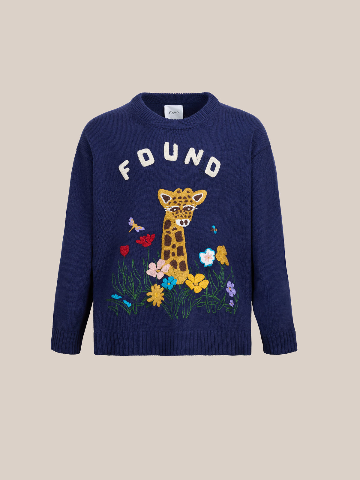 The Wildlife Knit Sweater by FOUND: a blue unisex crewneck featuring “FOUND” text, an embroidered giraffe, vibrant flowers, and butterflies.