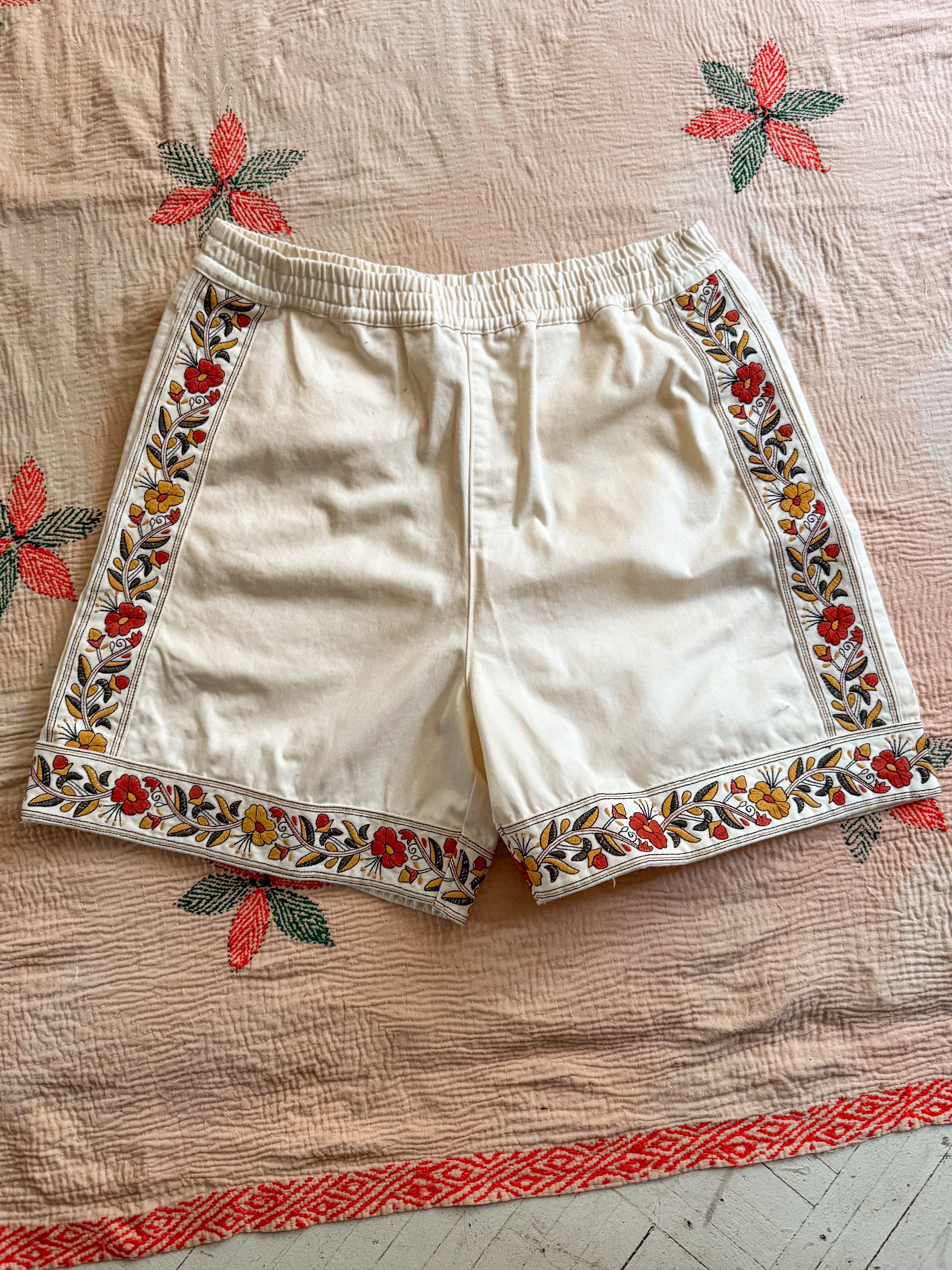 FOUND's Kantha Floral Work Shorts feature colorful floral embroidery on a backdrop of red and green leaves. Made from 100% cotton, these shorts seamlessly blend traditional craftsmanship with modern style.