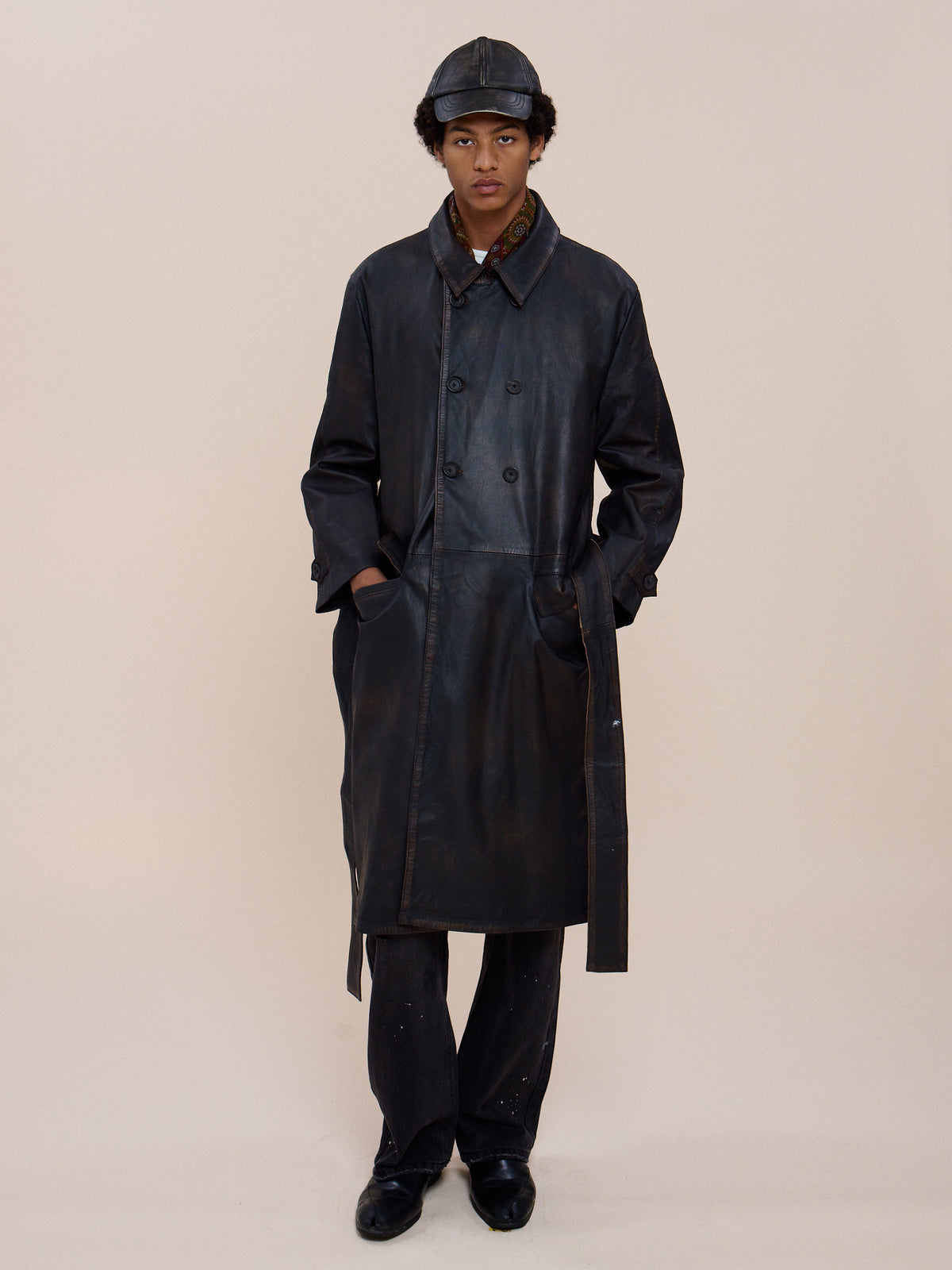 A person wears the FOUND Belted Leather Trench Coat and matching hat, standing with hands in pockets against a plain light background.