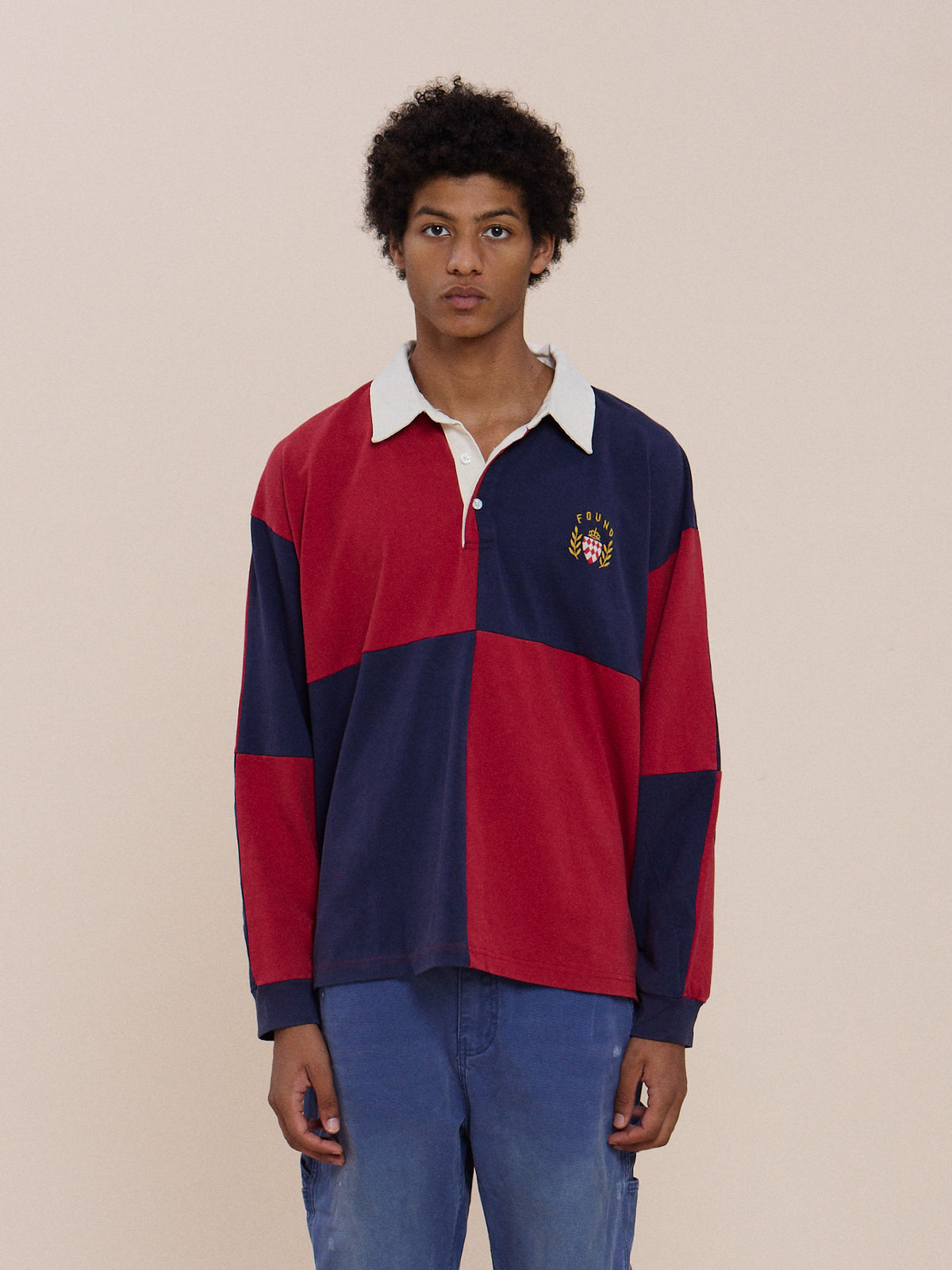 A young person stands against a plain background, wearing the FOUND Crestfield Rugby and blue pants.