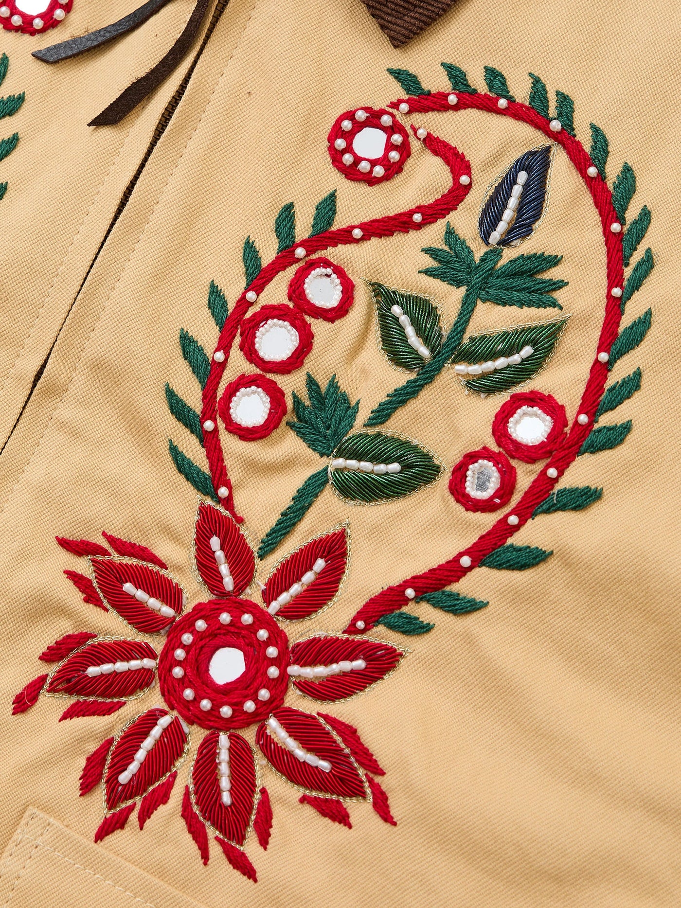 Close-up of Found's Paisley Motif Hand Embroidered Work Jacket in tan cotton twill, featuring red, green, and white floral embroidery with a large flower and leaf design that highlights artisan craftsmanship.