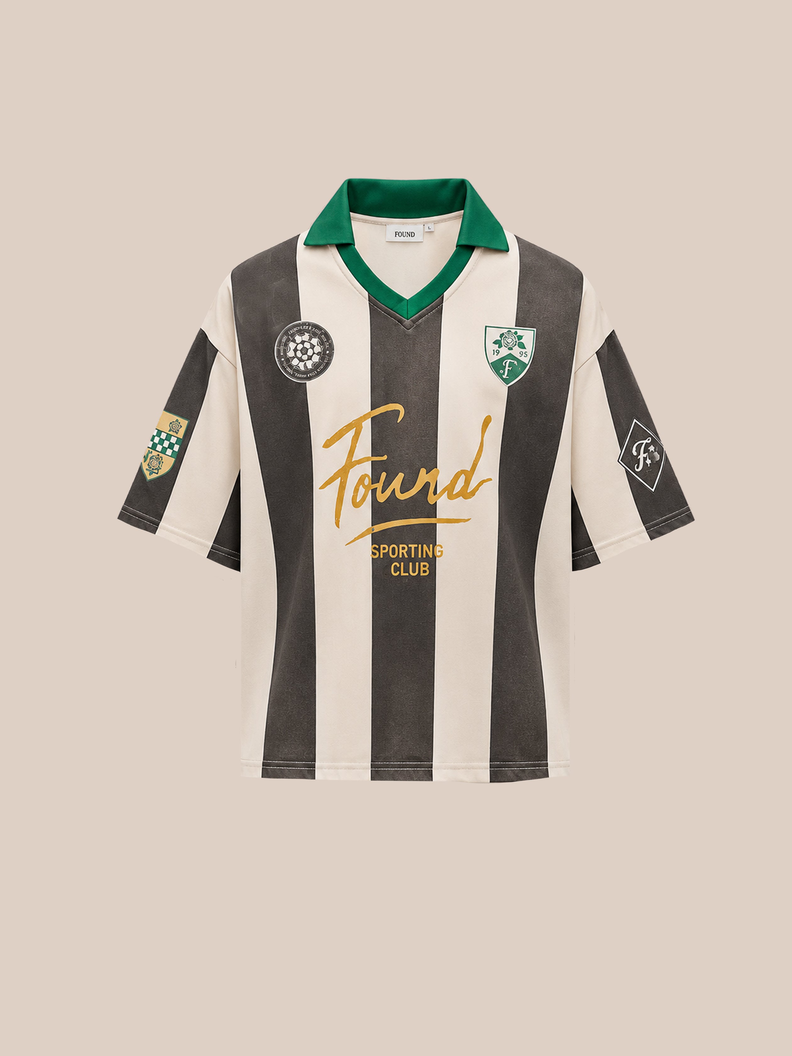 The FOUND Found Club Short Sleeve Jersey is a unisex football jersey with short sleeves, featuring classic black and white vertical stripes, a green collar, multiple patches, and “Found Sporting Club” printed in gold script on the front for a timeless retro sports shirt look.